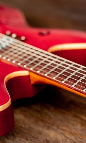 The red guitar that was laid on the floor of an old wooden plate.